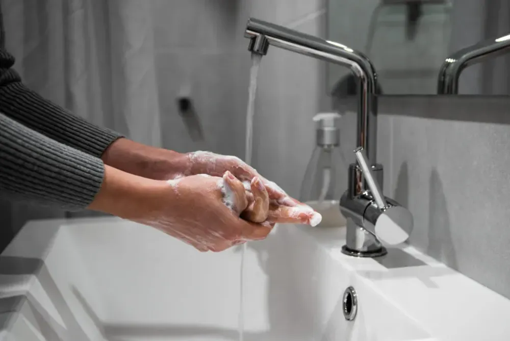 Close up of someone washing their hands in a grey and white bathroom